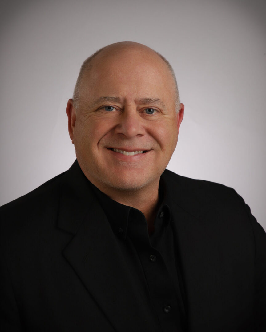 Smiling bald man in black suit headshot